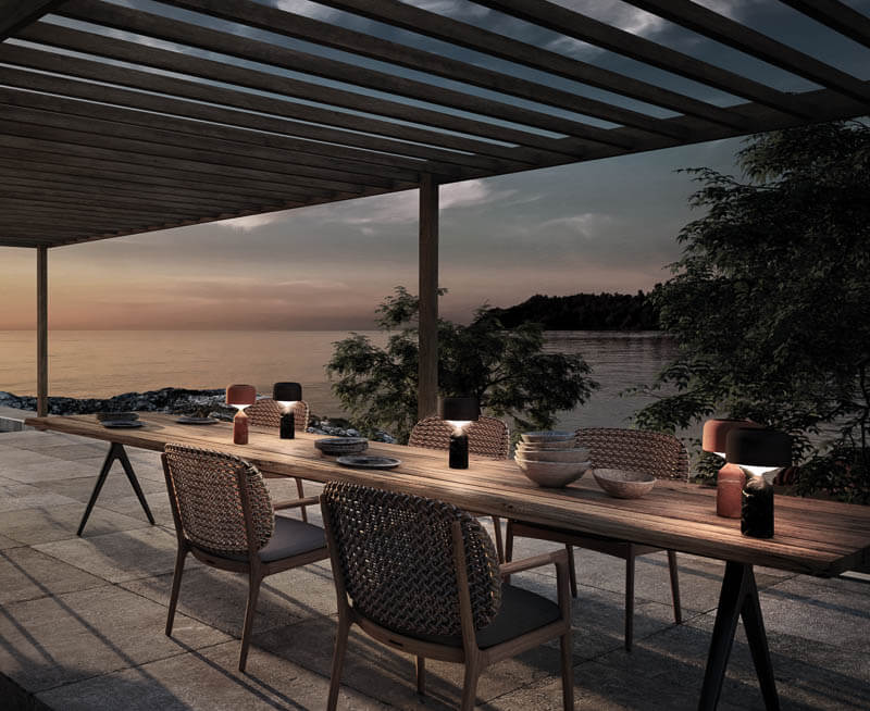 Portable table lamps from Gloster on a long outdoor dining table.